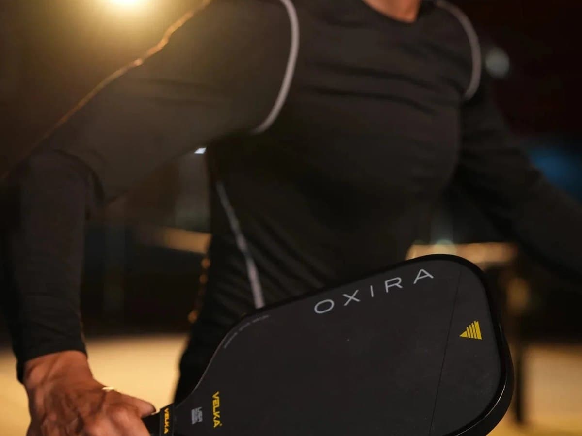 A player on a floodlit court holding a Velka Oxira paddle at the ready